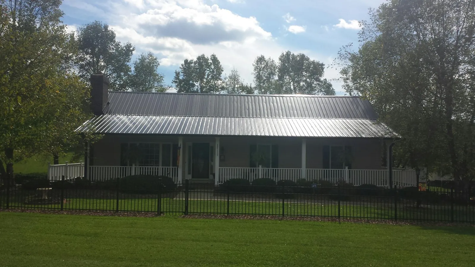 Gray metal roof on a brick ranch with a full width front porch — Gutter Guard Installation work by our crew in Leicester