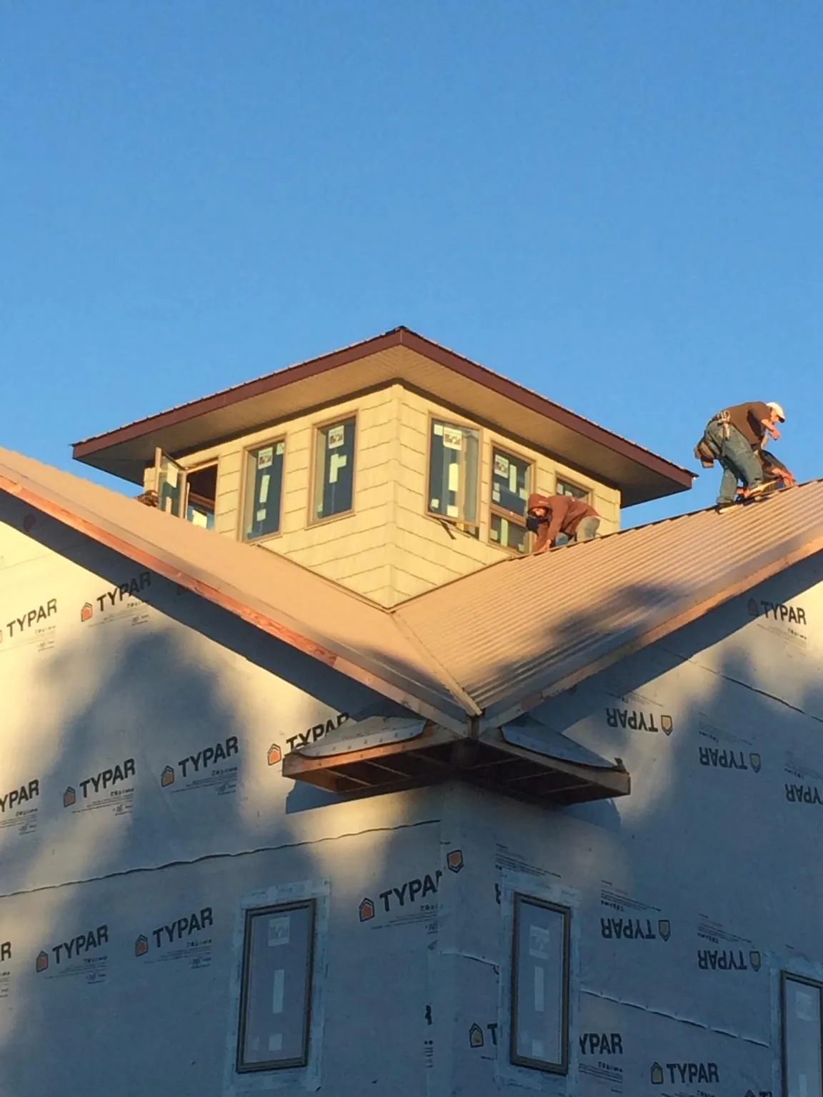 Roofers working around a rooftop cupola on a new metal roof at sunset — Roof Waterproofing in Leicester by Roofing Brothers